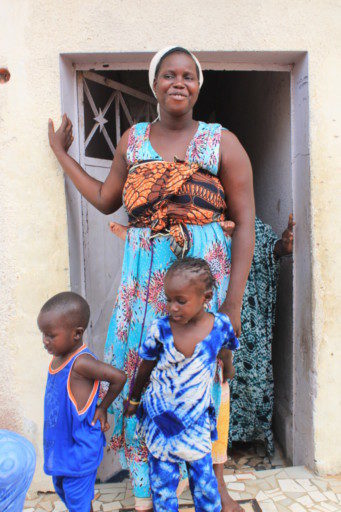 Una mamma senegalese esce di casa con i suoi bimbi per salutarci con calore africano 